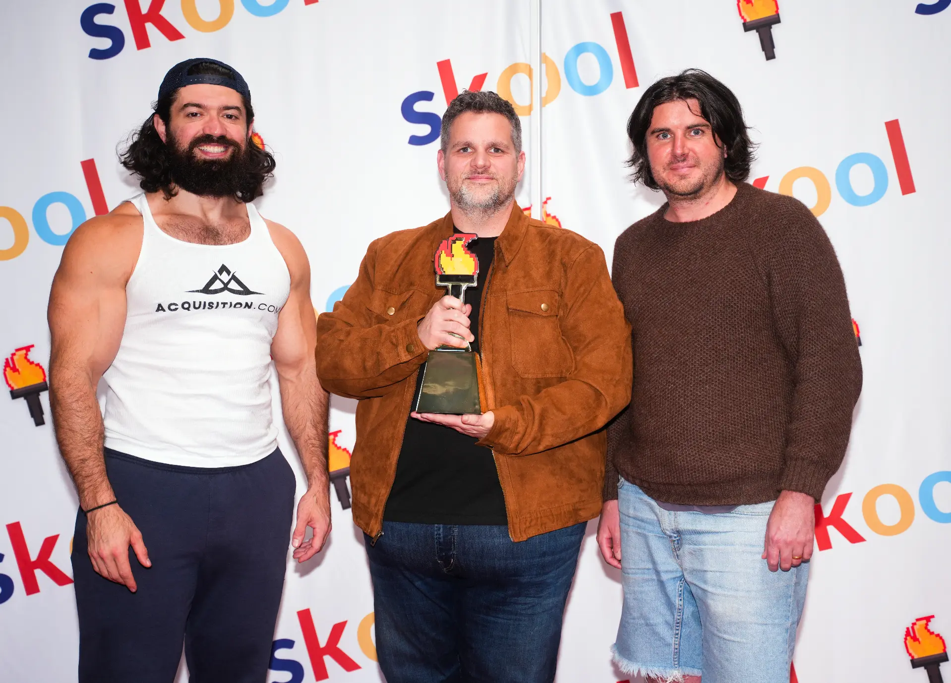 Jason Flamm accepting a Skool Games trophy from Alex Hormozi and Skool CEO Sam Ovens.